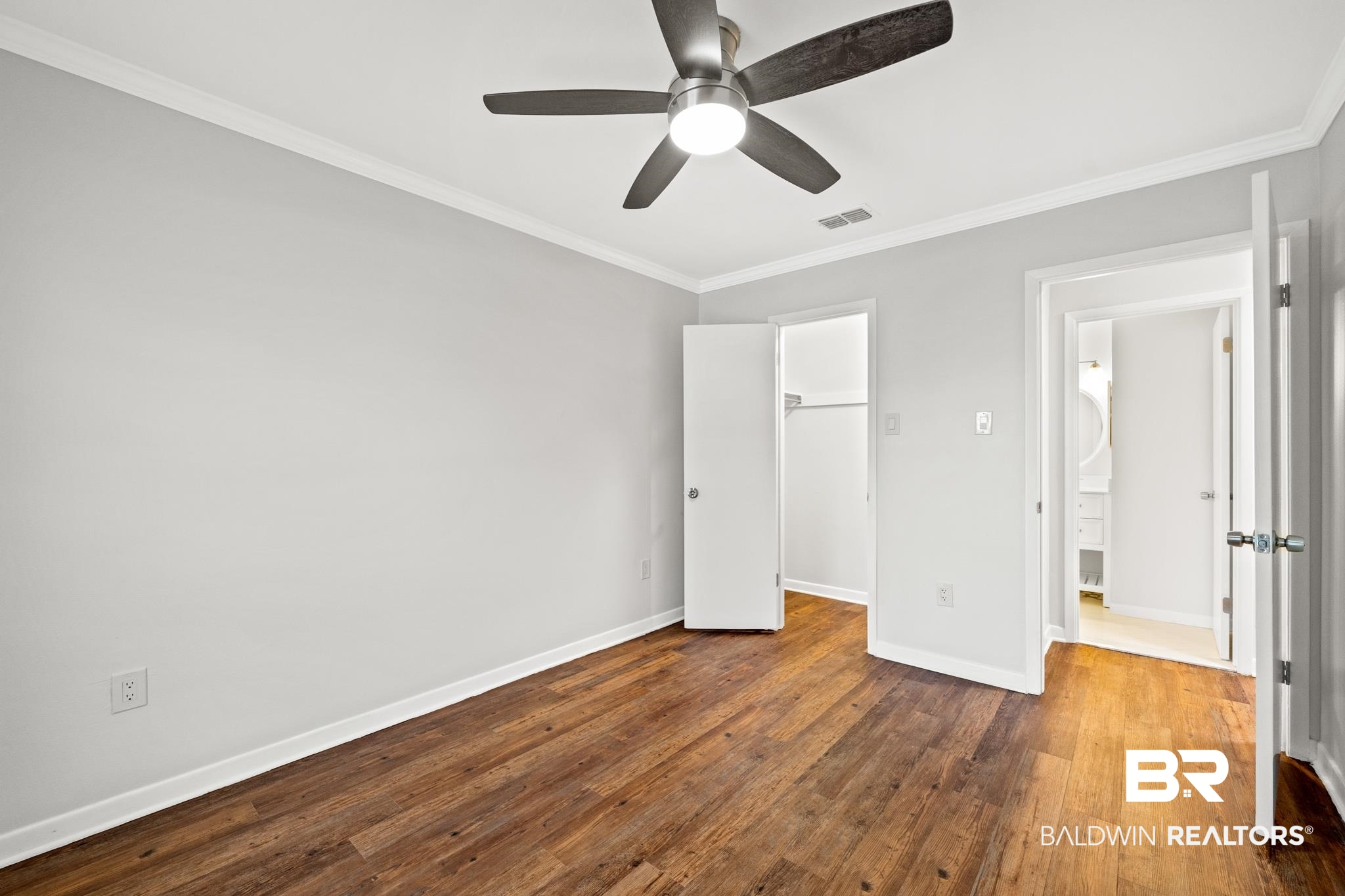 2901 Grant Street, Unit 802 Mobile, AL 36606 - Photo 26 of 37 Unfurnished bedroom featuring ornamental molding, a spacious closet, wood-type flooring, and ceiling fan