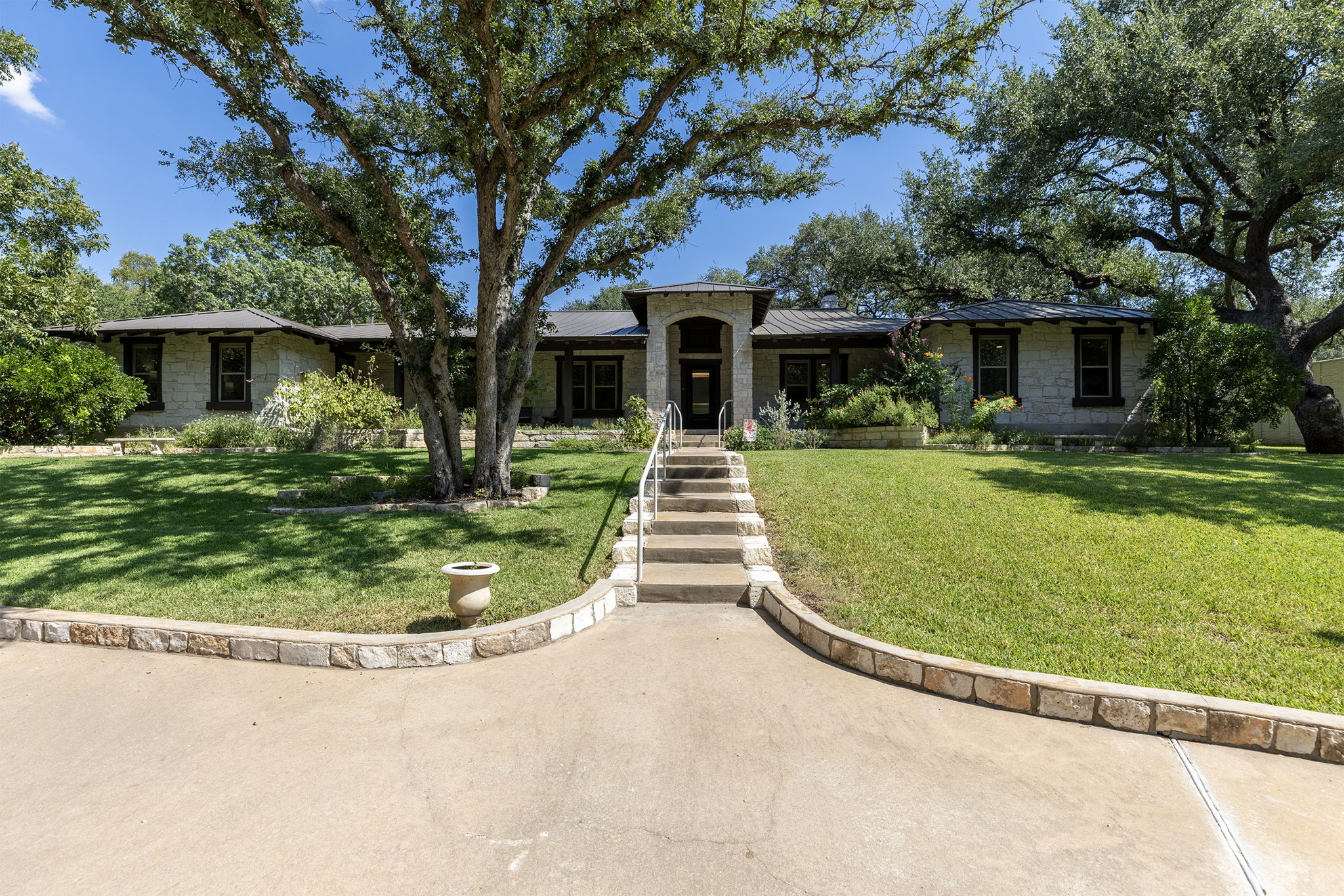 View of front of house with large front porch and many trees