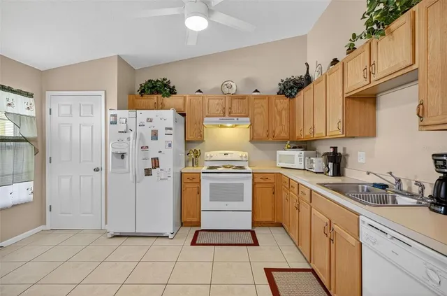 a kitchen with cabinets appliances a sink and a stove top oven