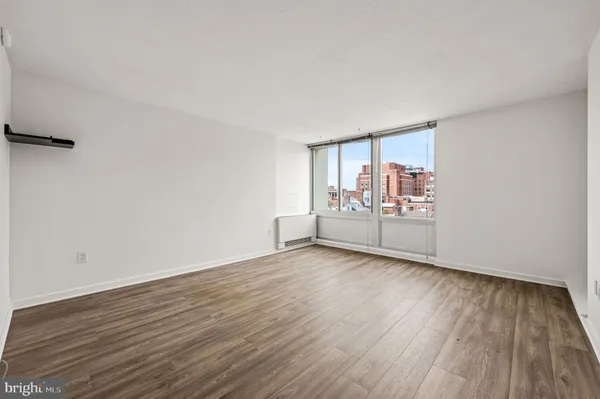 a view of an empty room with wooden floor and a window