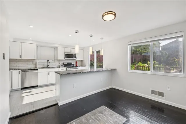 a kitchen with stainless steel appliances granite countertop a stove a sink and a microwave