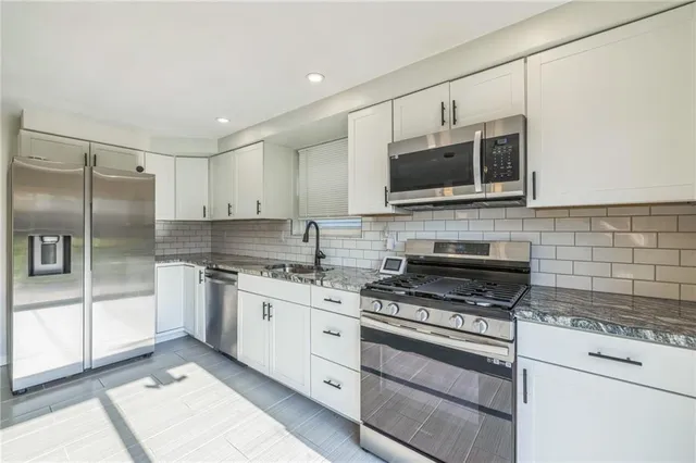 a kitchen with stainless steel appliances granite countertop a stove microwave and cabinets