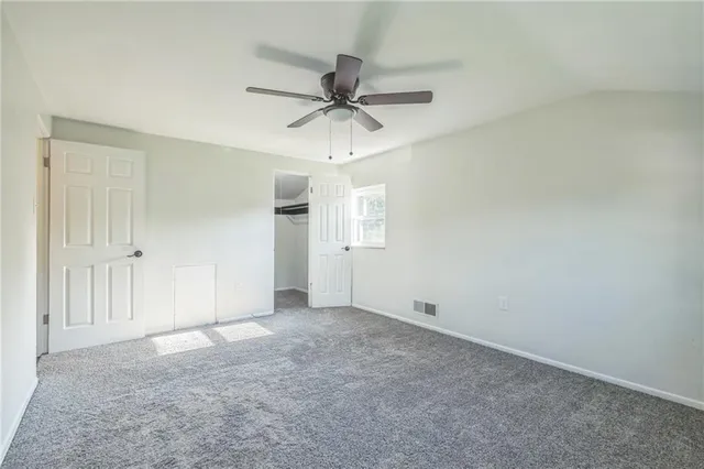 an empty room with chandelier fan and windows