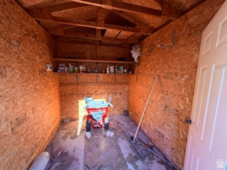 588 North 4500 West West Point, UT 84015 - Photo 56 of 61 Storage shed featuring OSB paneling, exposed rafters, built-in shelving, wall-mounted hooks, and a paneled door