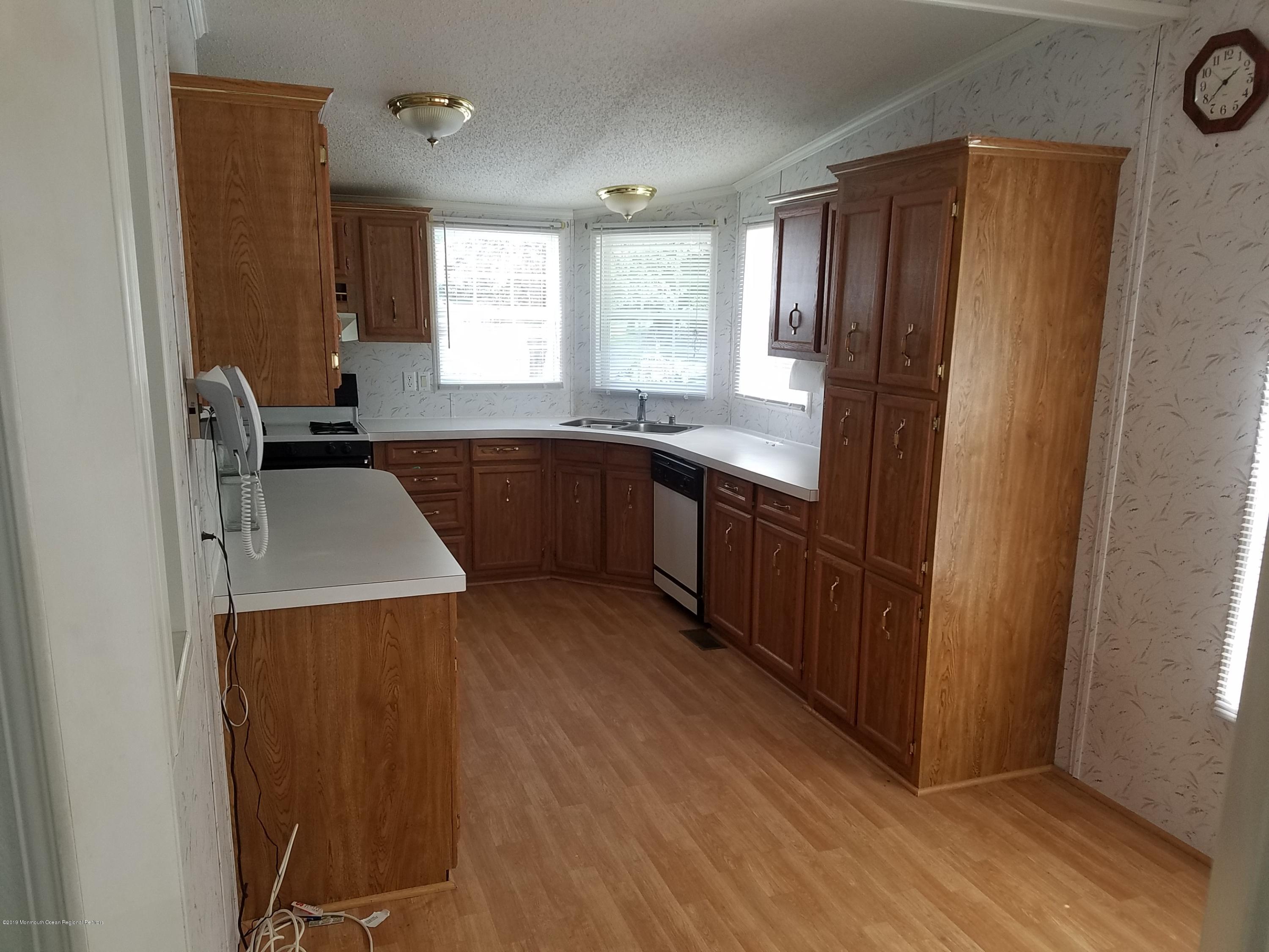 15 Village Road Morganville, NJ 07751 - Photo 2 of 12 a kitchen with stainless steel appliances granite countertop a refrigerator a sink dishwasher a stove and white countertops with wooden floor