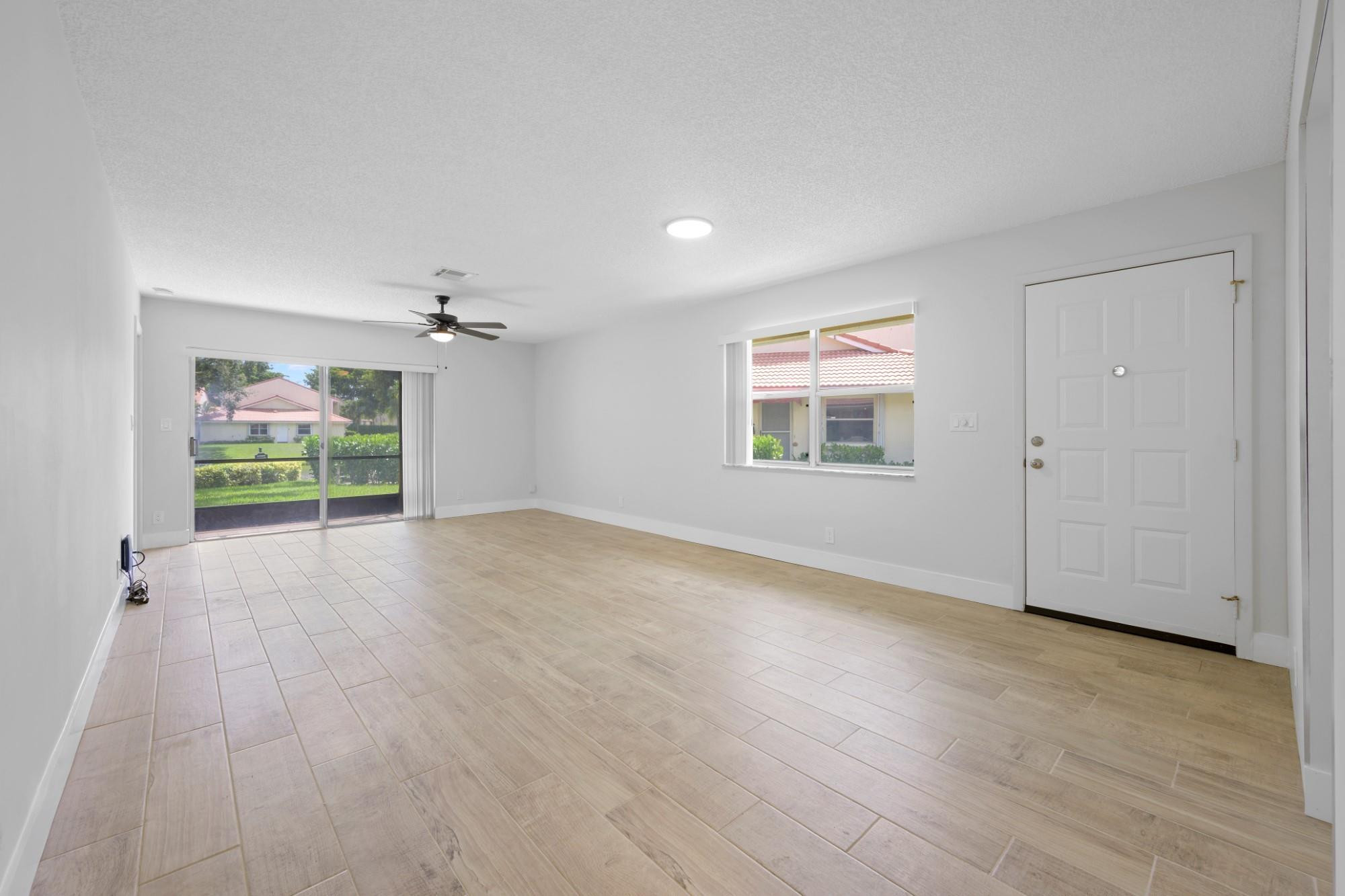 6371 Boca Circle Boca Raton, FL 33433 - Photo 8 of 24 an empty room with wooden floor chandelier and windows