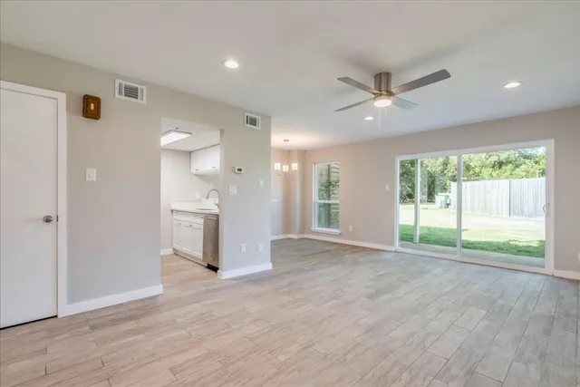 a view of an empty room with a window and wooden floor