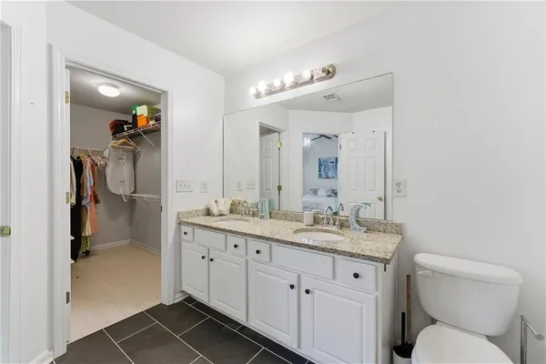 a bathroom with a granite countertop sink mirror vanity and toilet