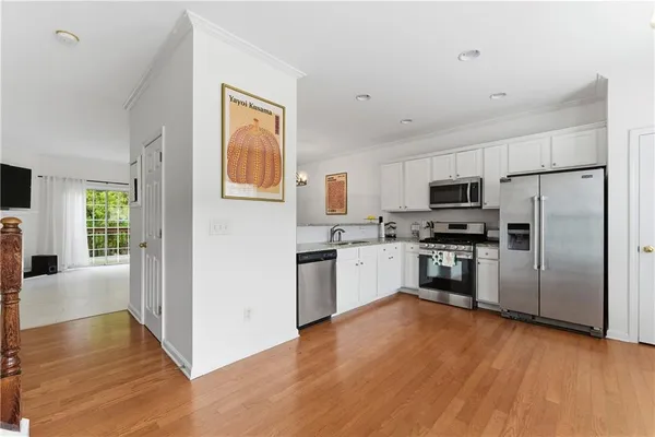 a kitchen with granite countertop a refrigerator cabinets and wooden floor