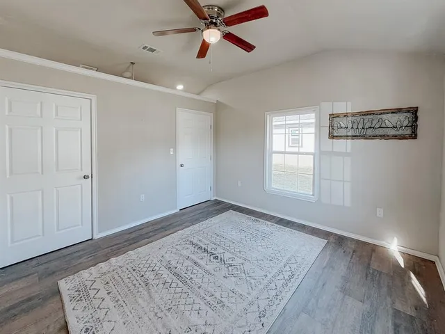 a view of empty room with wooden floor and fan