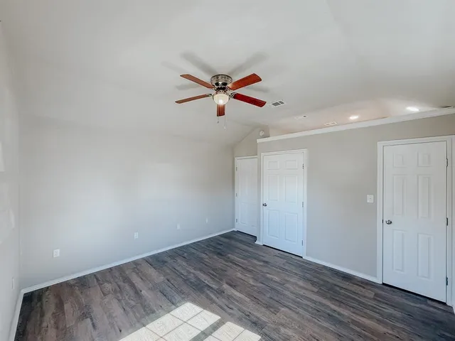 an empty room with wooden floor and fan