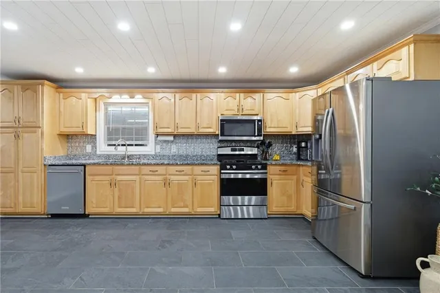 a kitchen with stainless steel appliances granite countertop a refrigerator a stove a sink and a microwave