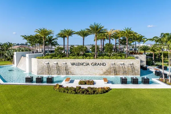 a view of a swimming pool with a yard and palm trees