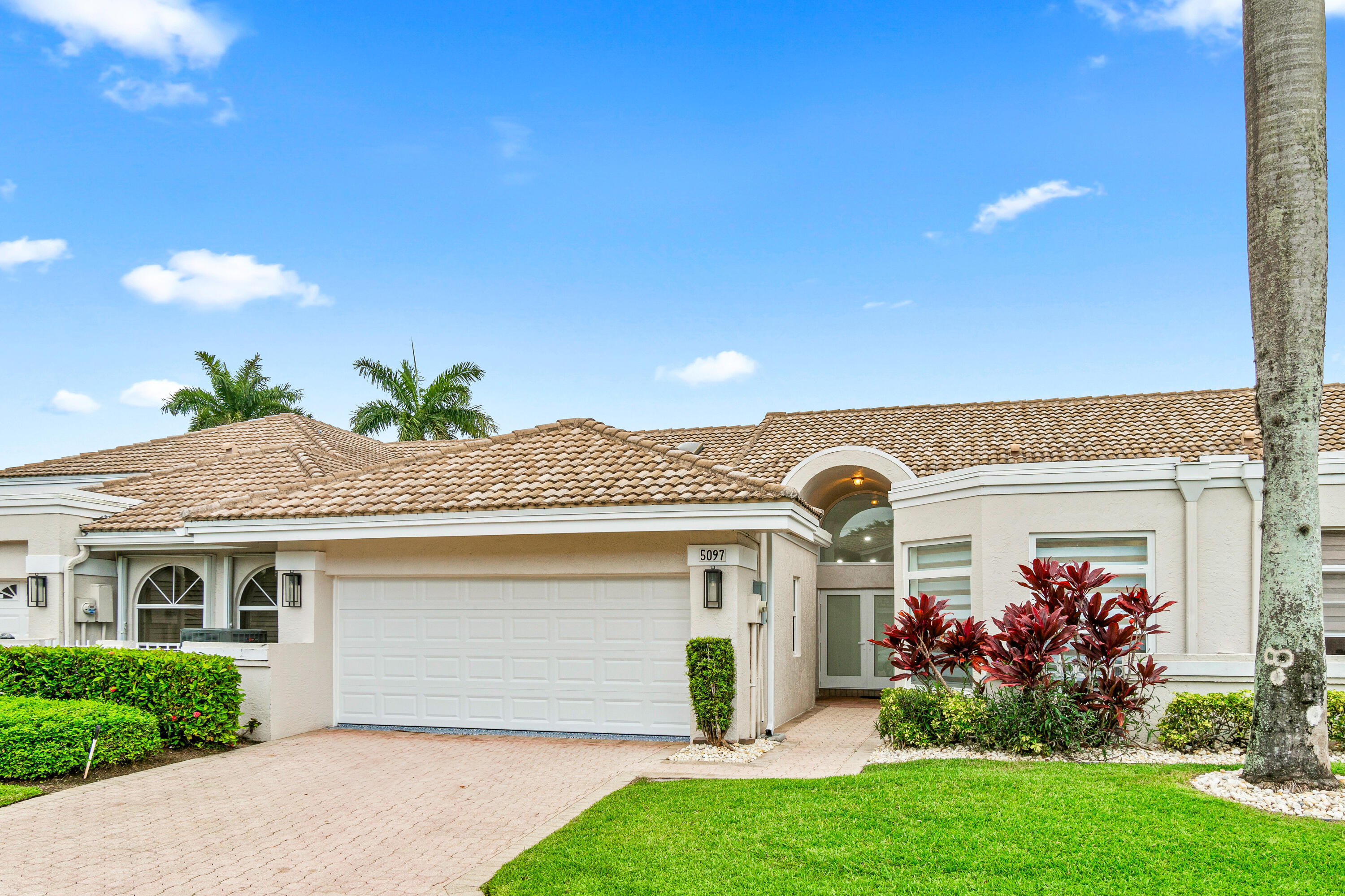 5097 Windsor Parke Drive Boca Raton, FL 33496 - Photo 2 of 30 a front view of a house with a garden and plants