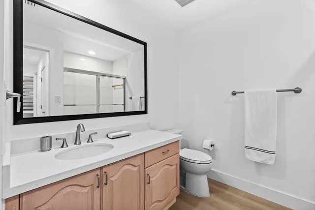 a bathroom with a granite countertop sink a toilet and a mirror