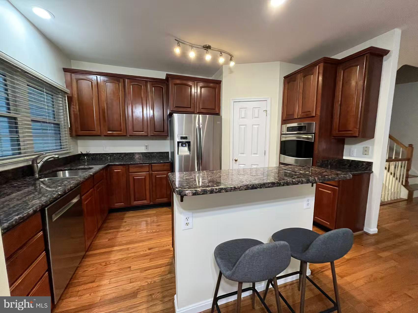 4102 Kentmere Square Fairfax, VA 22030 - Photo 21 of 55 a kitchen with stainless steel appliances granite countertop wooden cabinets a refrigerator a stove a sink and dishwasher with wooden floor