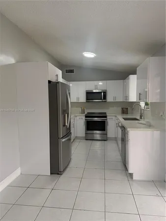 a kitchen with stainless steel appliances granite countertop a refrigerator and a stove top oven