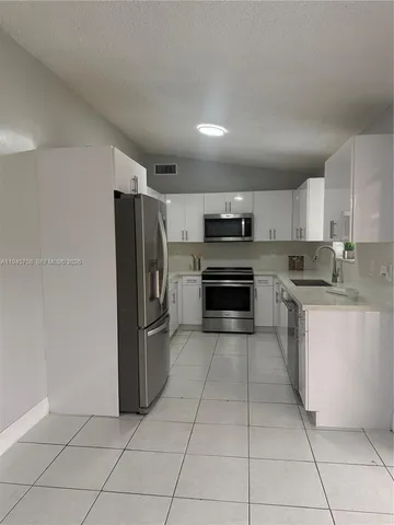 a kitchen with stainless steel appliances granite countertop a refrigerator and a stove top oven