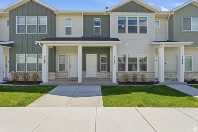 1173 West 1870 South Logan, UT 84321 - Photo 2 of 33 Modern townhome exterior featuring light gray siding, dark green vertical siding accents, white trim, and stone veneer detailing