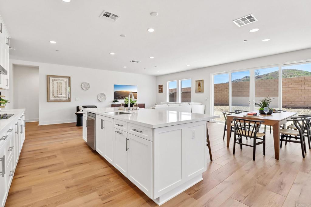 3521 Butler Place Escondido, CA 92027 - Photo 20 of 50 a large white dining hall with stainless steel appliances granite countertop a stove and a wooden floors