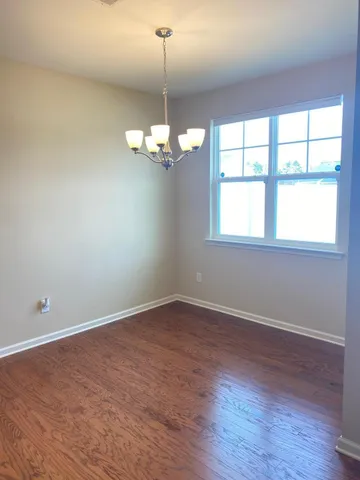 an empty room with wooden floor chandelier and windows