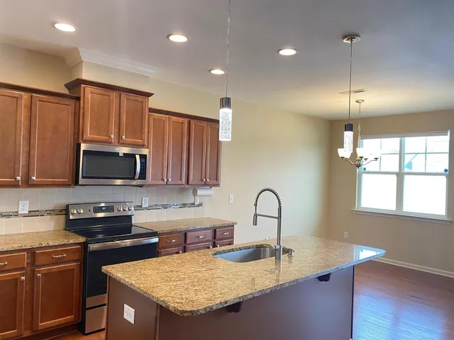 a kitchen with kitchen island granite countertop a sink a counter space appliances and cabinets