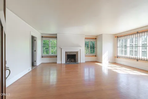 an empty room with wooden floor staircase and windows