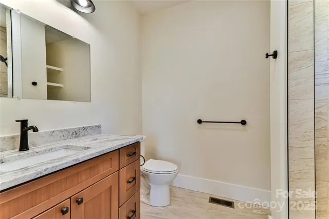 a bathroom with a granite countertop sink a toilet and a shower