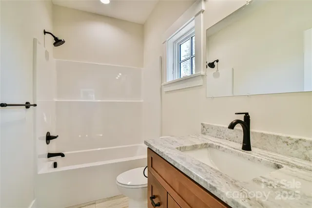a bathroom with a granite countertop sink a toilet and bathtub