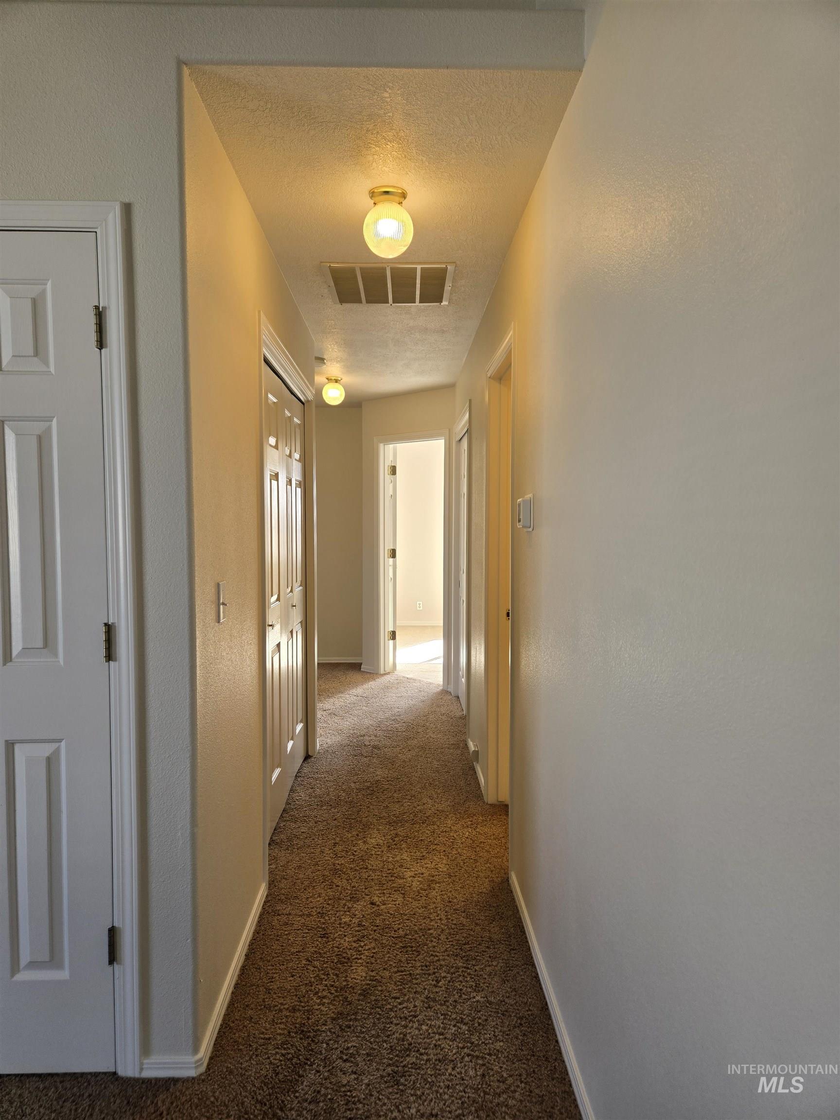 183 Southwest 18th Street Ontario, OR 97914 - Photo 15 of 32 Corridor with dark carpet, a textured ceiling, and a textured wall