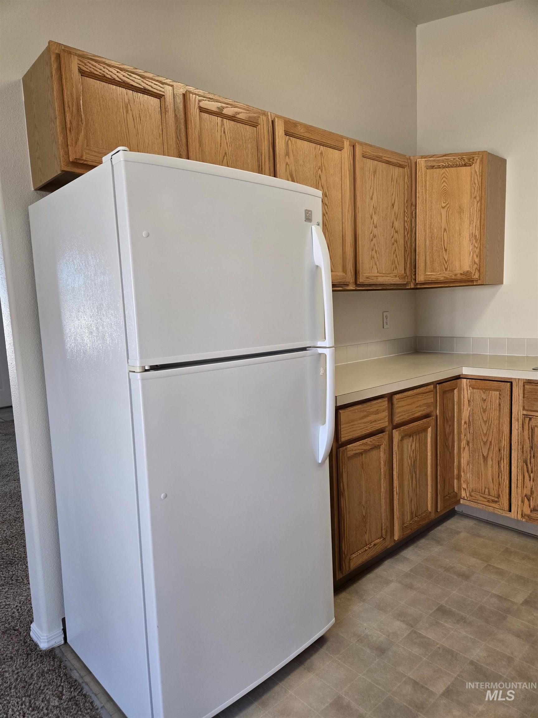 183 Southwest 18th Street Ontario, OR 97914 - Photo 9 of 32 Kitchen featuring freestanding refrigerator, light countertops, dark flooring, and wood finish cabinets