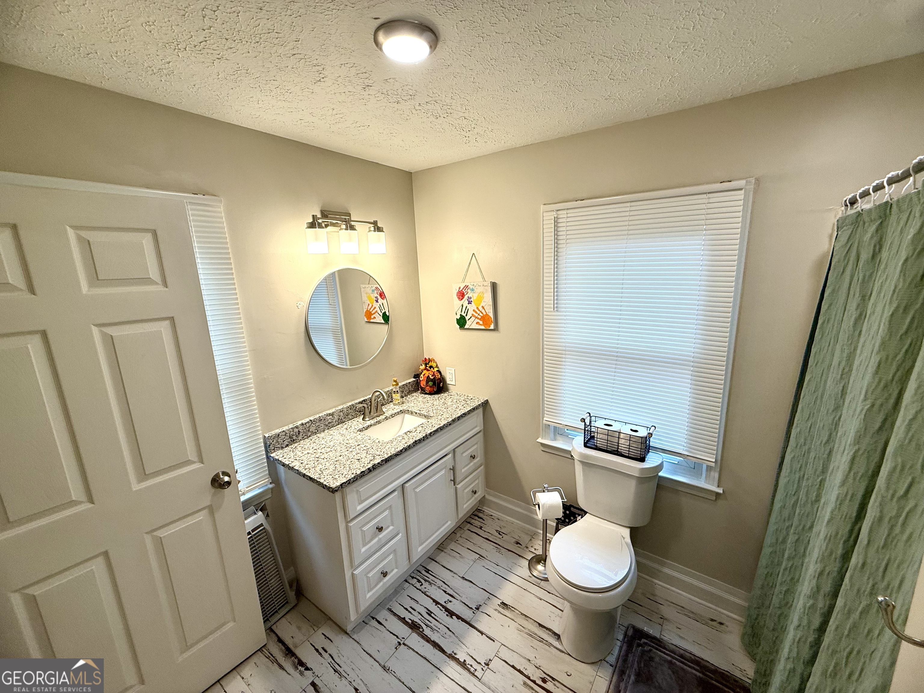 554 Spring Street Commerce, GA 30529 - Photo 43 of 58 a bathroom with a granite countertop toilet sink and mirror