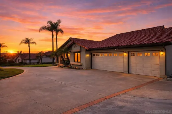 a view of a house with palm trees next to a yard
