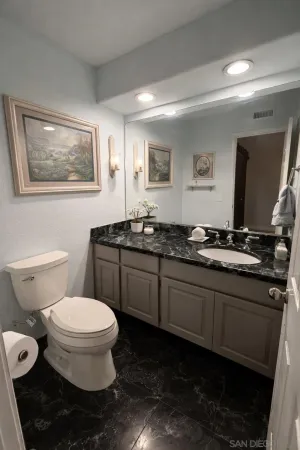 a bathroom with a granite countertop toilet sink and mirror
