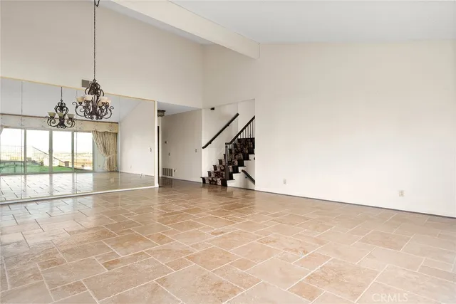 a view of empty room with stairs and chandelier
