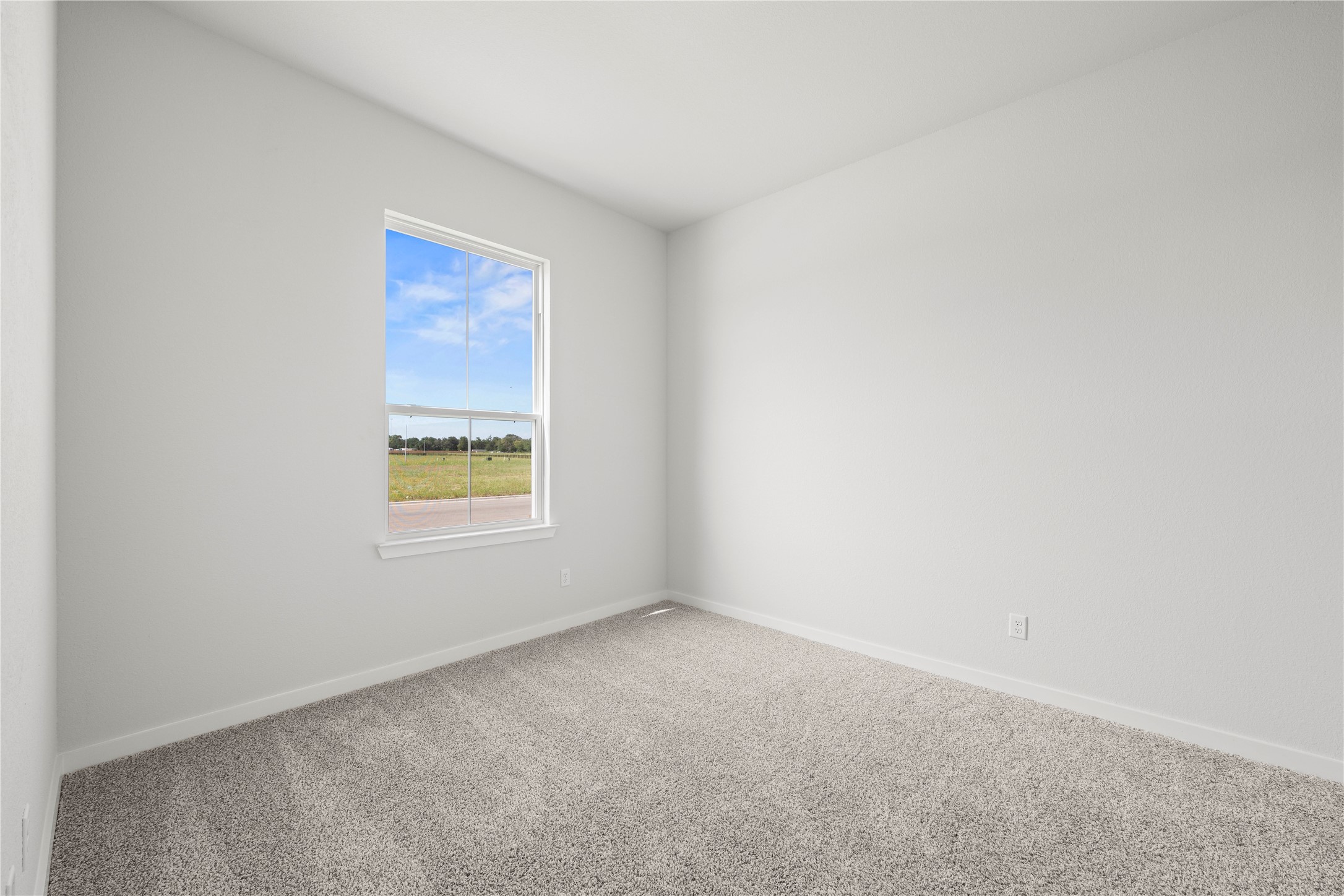 220 Gus Loop Georgetown, TX 78626 - Photo 5 of 18 A well-lit bedroom with fresh carpeting and a window overlooking a verdant landscape.