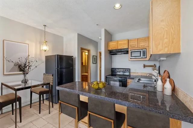 a kitchen with stainless steel appliances granite countertop a refrigerator a sink a stove and chairs