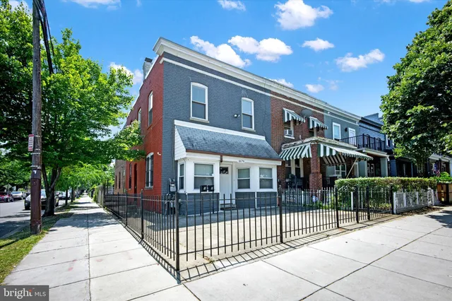 a view of a brick house with many windows next to a yard