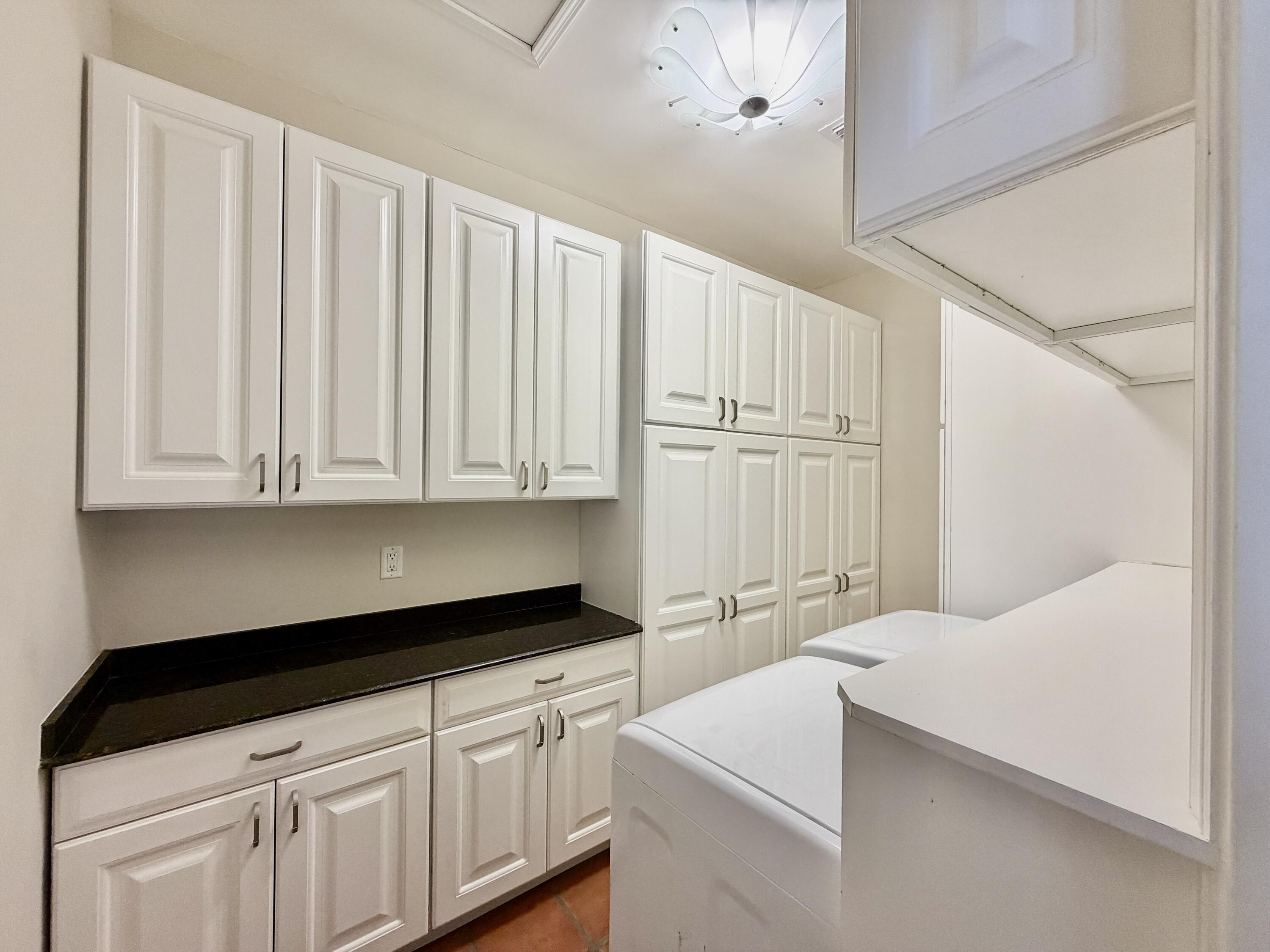 6401 Travis Road West Palm Beach, FL 33406 - Photo 36 of 99 a kitchen with white cabinets and clock