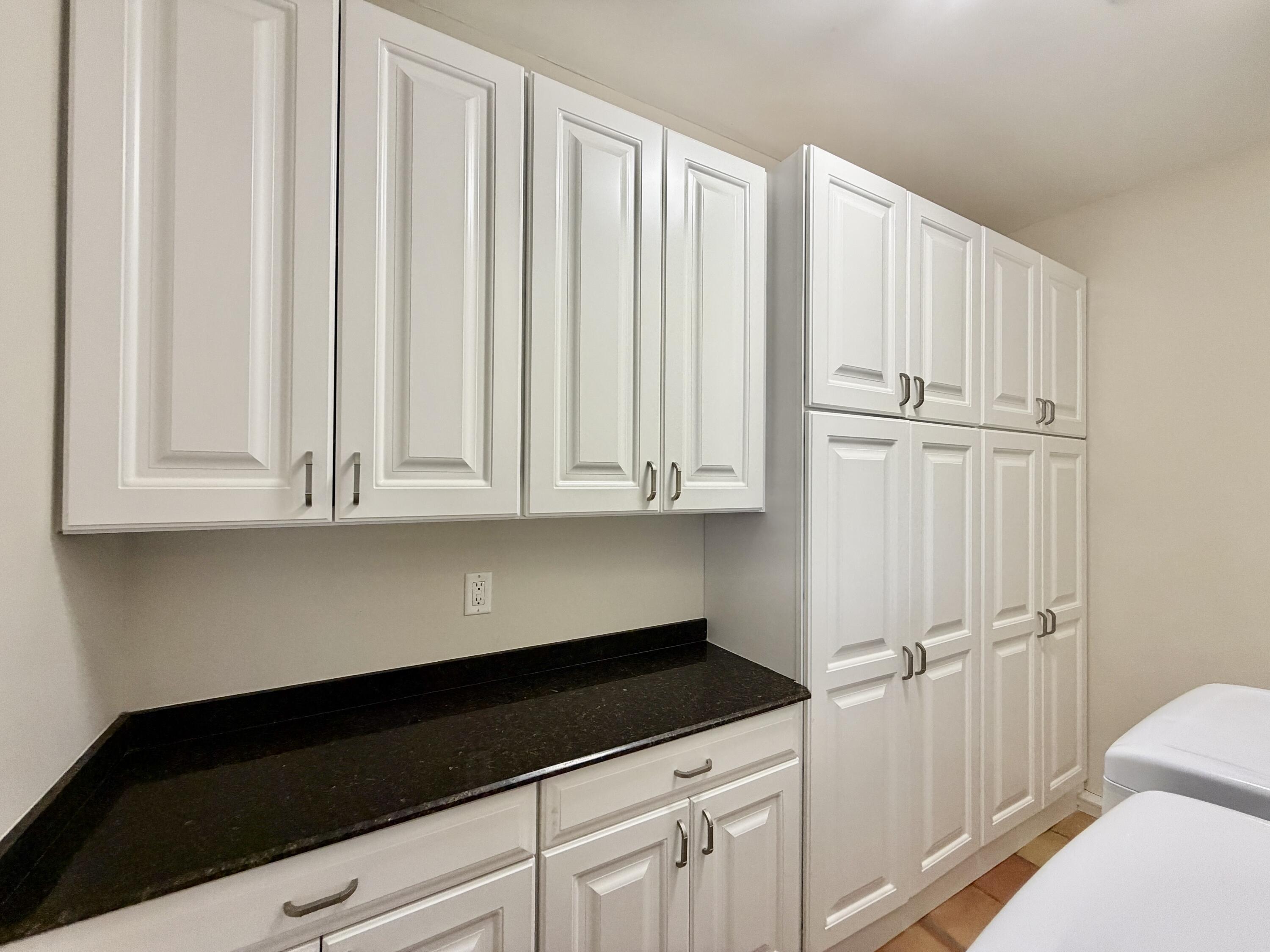 6401 Travis Road West Palm Beach, FL 33406 - Photo 37 of 99 a kitchen with white cabinets and black appliances