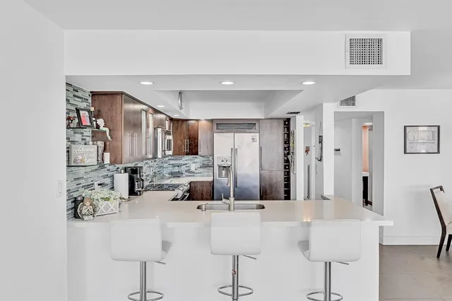 a kitchen with stainless steel appliances kitchen island granite countertop a refrigerator and a stove top oven