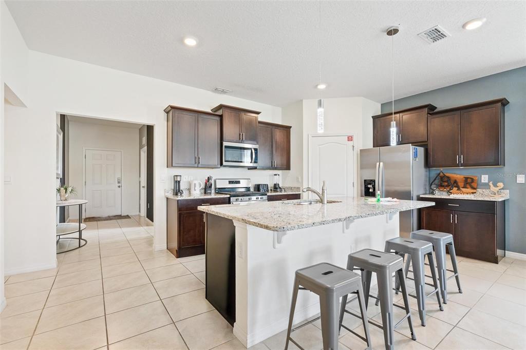 7841 Oak Reflection Loop Davenport, FL 33837 - Photo 13 of 44 a kitchen with stainless steel appliances kitchen island granite countertop a sink and cabinets