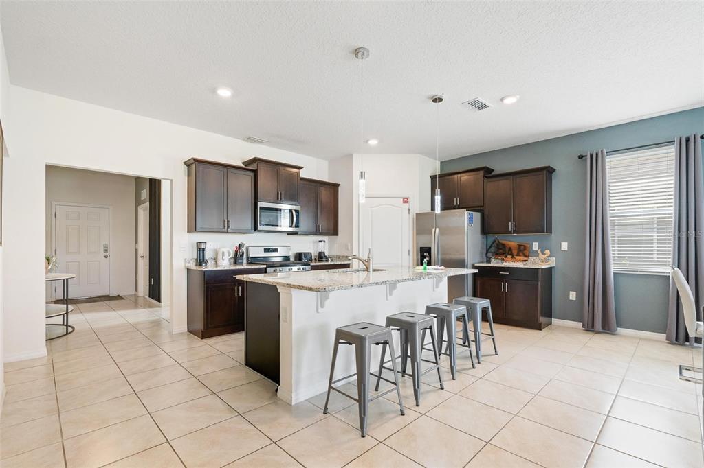 7841 Oak Reflection Loop Davenport, FL 33837 - Photo 14 of 44 a kitchen with granite countertop a refrigerator and a stove top oven