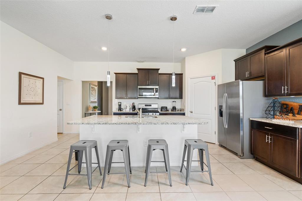 7841 Oak Reflection Loop Davenport, FL 33837 - Photo 16 of 44 a kitchen with stainless steel appliances granite countertop a refrigerator and a stove top oven