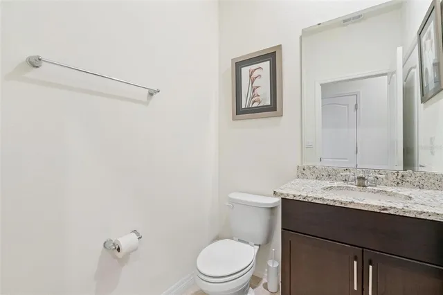 a bathroom with a granite countertop sink mirror vanity and toilet