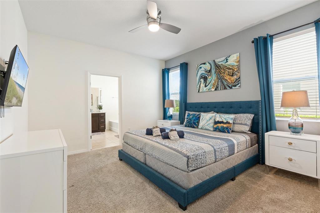 7841 Oak Reflection Loop Davenport, FL 33837 - Photo 22 of 44 a spacious bedroom with a bed and a flat screen tv