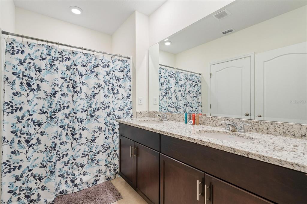 7841 Oak Reflection Loop Davenport, FL 33837 - Photo 28 of 44 a bathroom with a granite countertop sink a mirror and a shower