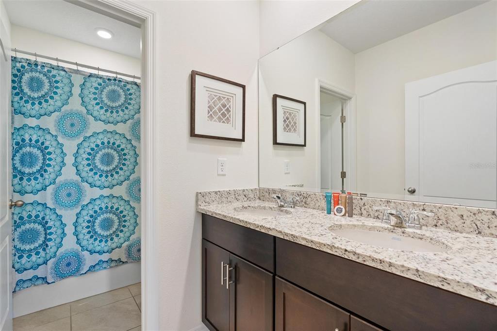 7841 Oak Reflection Loop Davenport, FL 33837 - Photo 30 of 44 a bathroom with a granite countertop sink mirror and painting on the wall