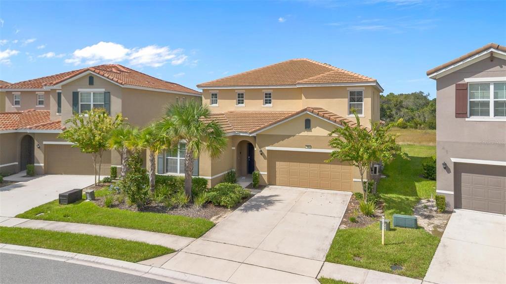 7841 Oak Reflection Loop Davenport, FL 33837 - Photo 3 of 44 a front view of a house with a yard and potted plants
