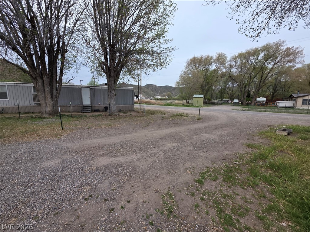 101 Ada Street, Unit 12 Caliente, NV 89008 - Photo 7 of 14 A tranquil rural setting with mature trees and a functional gravel driveway.